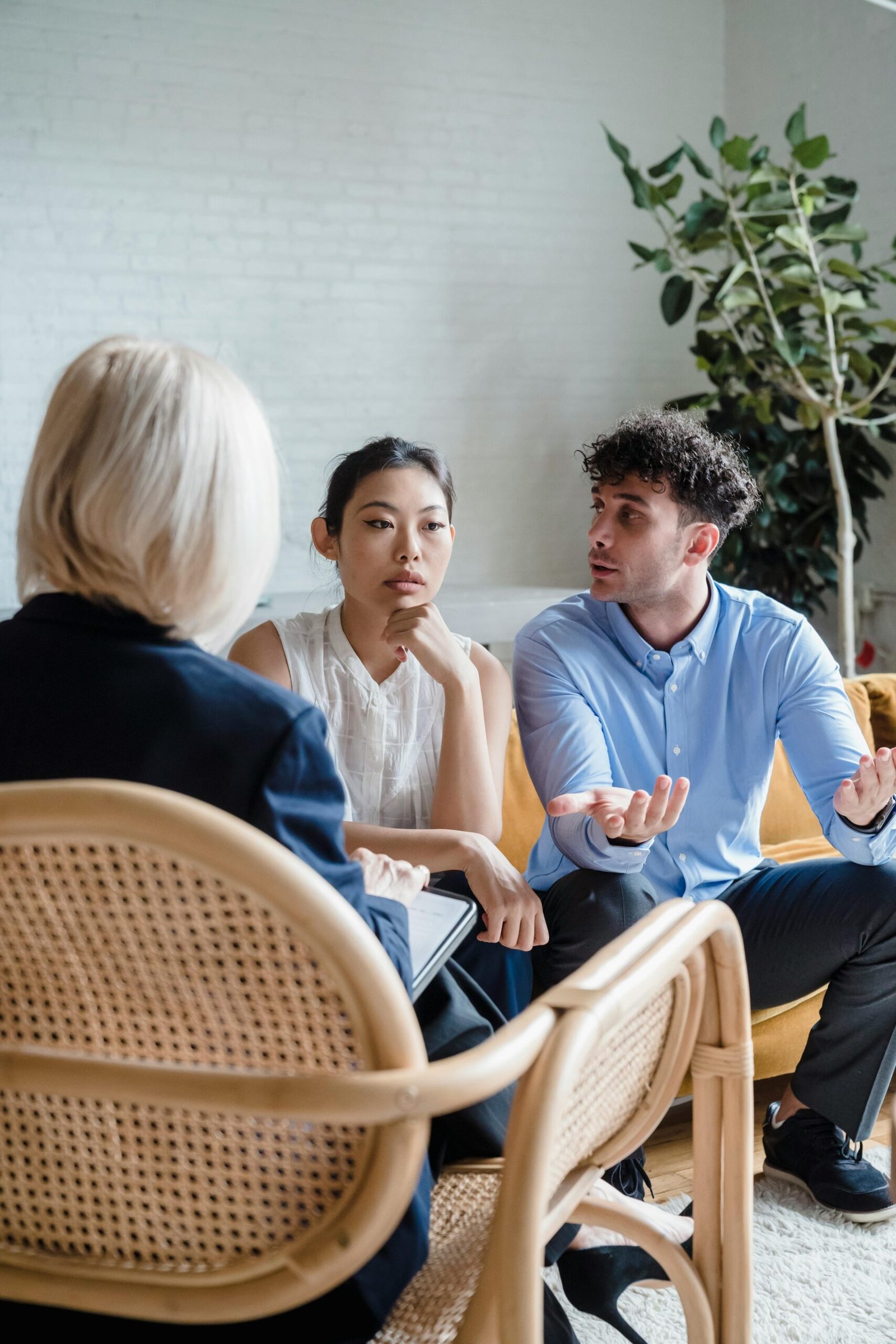 A couple discusses issues with a therapist in a modern office setting.